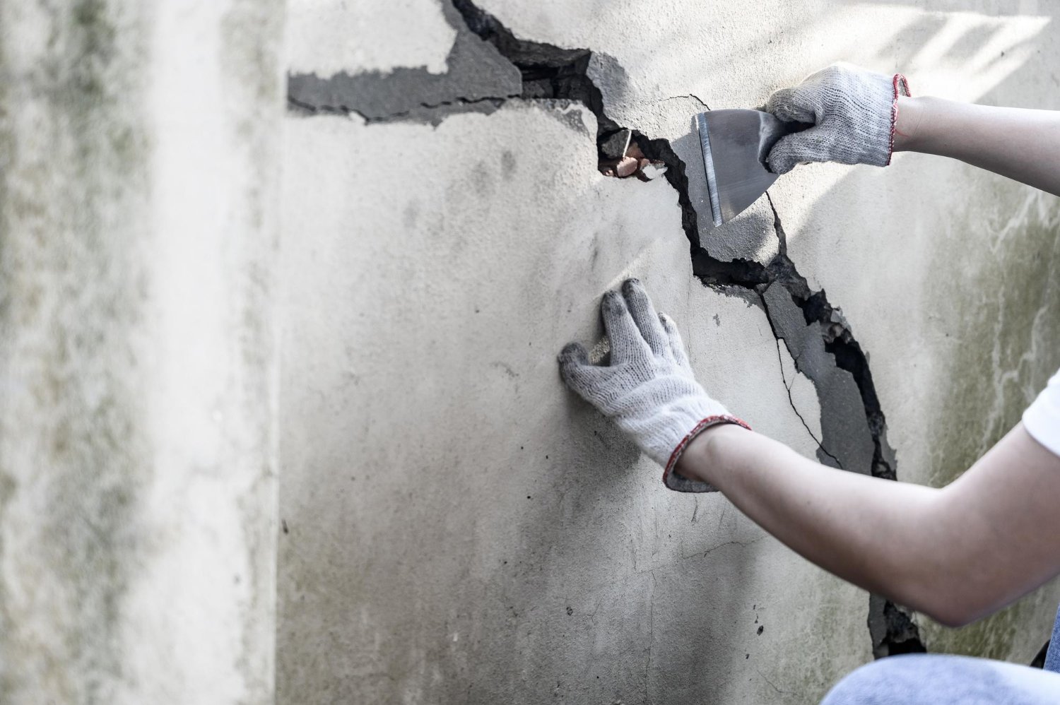 A man is busy repair a concrete wall with a hammer