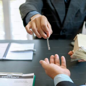 Two businesspeople completing a real estate transaction; one hands over a key while the other gives a bundle of cash, with a contract and notebook on the table